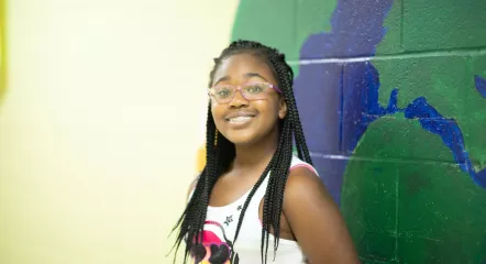 Youth smiling in front of a map on the wall.