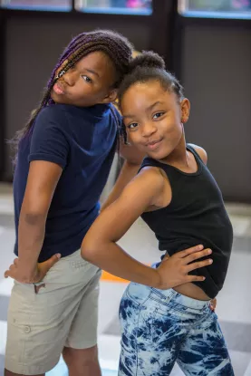 Youth standing back to back with hands on hips.