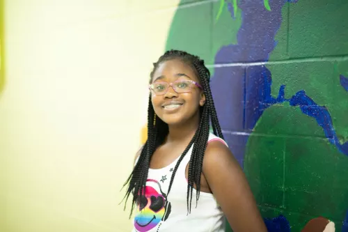 Youth smiling in front of a map on the wall.