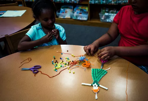 Youth creating with string and beads.