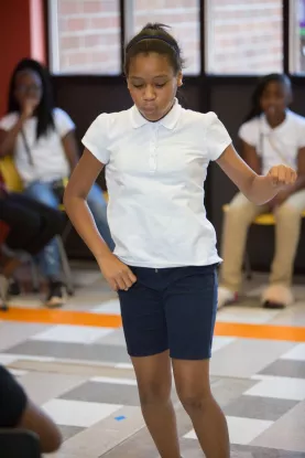 Youth standing with one arm up and one arm down